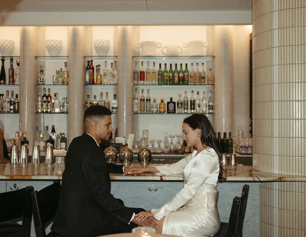 a couple sitting at a well stocked bar fora chicago with their hands on the counter