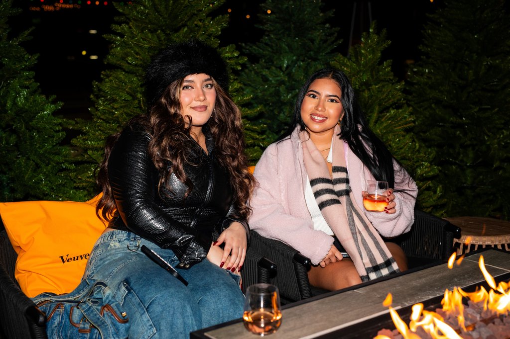 two girls enjoy their drinks by fire place at stones throw curling at the emily hotel chicago fulton market